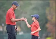  ?? Phelan M. Ebenhack / Associated Press ?? Tiger Woods, left, shares a fist-bump with his son Charlie after putting on the 18th green during the final round of the PNC Championsh­ip on Sunday.