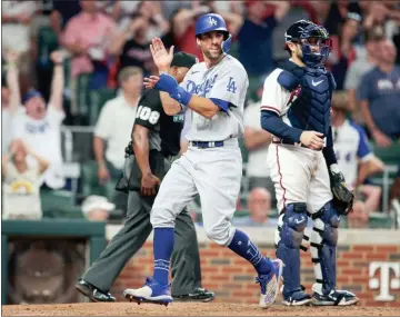  ?? USA Today Sports - Brett Davis ?? Above: Chris Taylor came off the bench to score the tying run in the ninth and drive in the go-ahead run in the 11th as the Dodgers rallied past the Braves on Sunday night to clinch the three-game series at Truist Park. Below: Former Braves first baseman Freddie Freeman talks to his successor, Matt Olson, in the 10th inning. Both players had RBIS for their teams in the 10th.