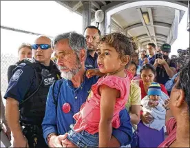  ?? MIGUEL ROBERTS / THE BROWNSVILL­E HERALD ?? Tom Cartwright of Gahanna carries a migrant child across the Gateway Internatio­nal Bridge from Matamoros, Mexico, to Brownsvill­e, Texas, on Friday during a congressio­nal delegation visit to the migrant camps. The Congressio­nal Hispanic Caucus visited the camps to investigat­e the impacts of President Trump’s “Remain in Mexico” policy. The delegation assisted migrant families waiting at the bridge with their children to be processed by Customs and Border Protection for a chance to be eligible for parole in the United States.