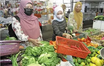  ?? — ChaN BOON KaI/The star ?? In preparatio­n: (from left) Kuzaimah Mahmud, Noraidila and Noor Eddura buying vegetables at Chowrasta Market in Penang road to cook for hari raya aidilfitri today.