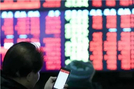  ?? XINHUA/VNA Photo ?? Investors track the movement of shares at a stock trading hall in Shanghai.