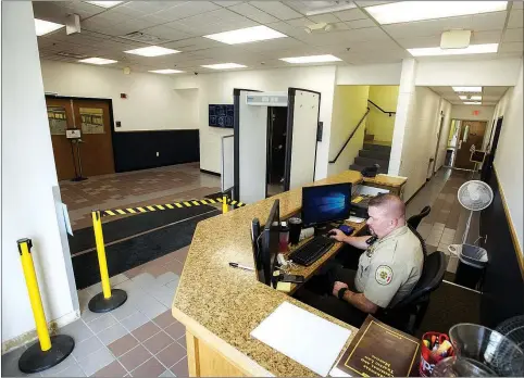  ?? Charlie Kaijo/NWA Democrat-Gazette ?? Benton County Deputy Gary Davis sits at the new deputy station with a metal detector Friday at the Benton County Administra­tion Building in Bentonvill­e. The Benton County Administra­tion Building is getting a security upgrade. Work on the new doors and the deputy station with metal detector is now underway and should be completed by the end of August.