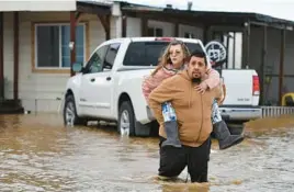  ?? JOSE CARLOS FAJARDO/BAY AREA NEWS GROUP ?? Ryan Orosco carries his wife, Amanda, from their home Monday in Brentwood, Calif. Twenty storm-related deaths have occurred recently.