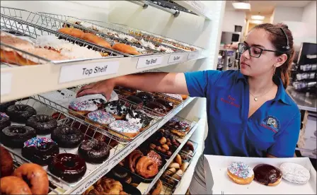  ?? PHOTOS BY SEAN D. ELLIOT/THE DAY ?? Assistant Manager Cassie Bingham gathers a dozen doughnuts for a customer at the newest Baker’s Dozen in the Bestway on Route 12 in Gales Ferry Monday.