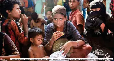  ??  ?? A Rohingya woman and her children eat after arriving at the port in Julok in Kuta Binje, Aceh Province, Indonesia (Representa­tional Image)