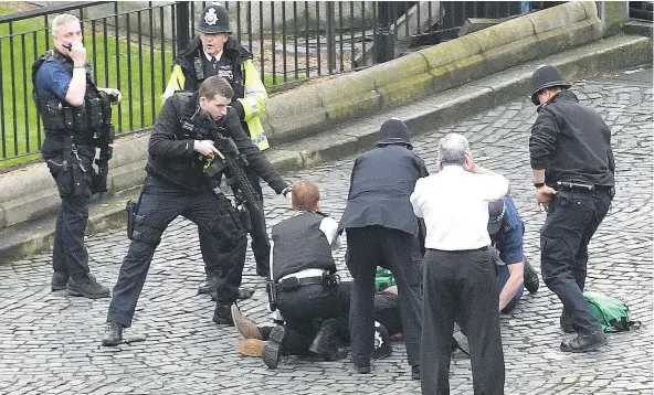  ?? — THE ASSOCIATED PRESS ?? A policeman points a gun as emergency services attend the scene outside the Palace of Westminste­r in London on Wednesday. It was the worst terror attack in London since the 2005 Tube bombings, and the worst on Parliament since the days of the IRA.