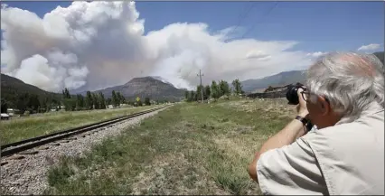  ?? MCBRIDE/THE DURANGO HERALD VIA AP ?? In this Saturday, photo, Paul Boyer of Durango, Colo., levels his camera for a shot of the plume as it rises from the wildfire near Hermosa, Colo. JERRY