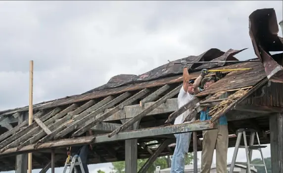  ?? Emily Matthews/Post-Gazette photos ?? Coraopolis Mayor Shawn Reed, left, and Henry Thompson, of Zelienople, remove parts of the passenger canopy near the train tracks as part of phase two of the Coraopolis Train Station Project earlier this month.