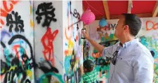  ??  ?? Taoiseach Leo Varadkar writes “Leo” at a graffiti wall at the Laya Healthcare City Spectacula­r in Dublin’s Merrion Square yesterday. Photo: Marc O’Sullivan