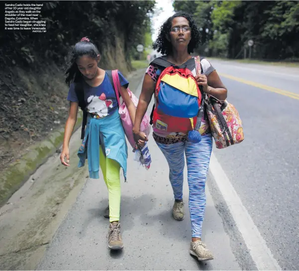  ?? PHOTOS / AP ?? Sandra Cadiz holds the hand of her 10-year-old daughter Angelis as they walk on the shoulder of the road near Dagota, Colombia. When Sandra Cadiz began struggling to feed her daughter, she knew it was time to leave Venezuela.