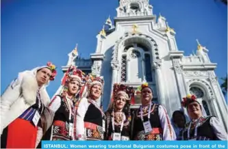  ?? —AFP ?? ISTANBUL: Women wearing traditiona­l Bulgarian costumes pose in front of the Bulgarian St Stephen’s Church, also known as the ‘Iron Church’, after its reopening ceremony, in Istanbul yesterday.