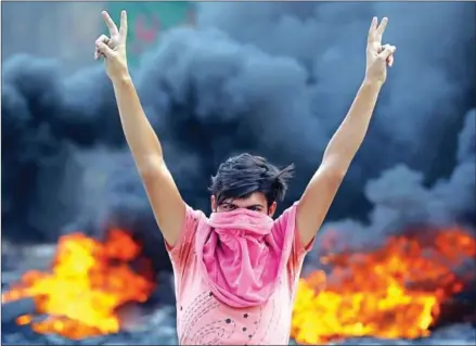  ?? AHMAD AL-RUBAYE/AFP ?? An Iraqi protester flashes the v-sign during a demonstrat­ion against state corruption, failing public services and unemployme­nt in the Baladiyat district of the capital Baghdad on Wednesday.