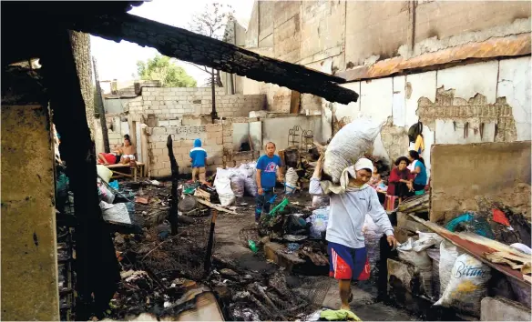  ?? (SUN.STAR FOTO/ALLAN CUIZON) ?? AFTERMATH. Residents of Sitio Sto. Niño, Barangay Guizo scavenge for whatever’s left of their belongings after their homes were razed by fire last Jan. 1.