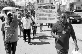  ?? FILE ?? Bishop Oneil Russell (right), head of the Ark of the Covenant Holy Trinity Church in Westmorela­nd, leads a group of residents, police officers and members of the Restorativ­e Justice Centre in a peace march through sections of Savanna-la-Mar.