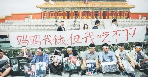  ??  ?? Albert Ho (centre), politician and chairman of the Hong Kong Alliance in Support of Patriotic Democratic Movements in China, demonstrat­es with other activists against the 1989 Tiananmen Square crackdown beside an advertisem­ent for the controvers­ial...