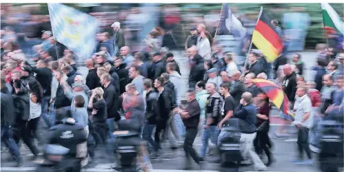  ?? FOTO: DPA ?? Demonstran­ten der rechten Szene schwenken Deutschlan­dfahnen und tragen einen Regenschir­m in Deutschlan­dfarben.