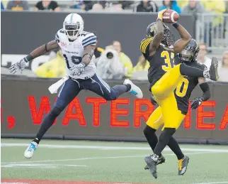  ?? PETER POWER/THE CANADIAN PRESS ?? Hamilton Tiger-Cats defensive back Richard Leonard picks off a pass intended for Toronto Argonauts slotback S.J. Green during the first half in Hamilton on Monday night.