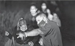  ??  ?? A Hidalgo County Precinct 3 deputy constable guides migrant families to a Border Patrol processing area in Mission last month. The migrants had surrendere­d to Border Patrol agents.