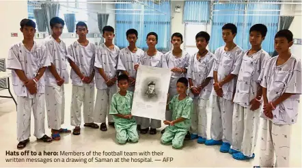  ??  ?? Hats off to a hero: Members of the football team with their written messages on a drawing of Saman at the hospital. — AFP