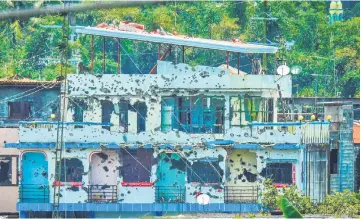  ?? — AFP photo ?? Bullet-riddled houses are seen in Marawi on the southern island of Mindanao. Soldiers killed 10 suspected militants as they attempted to infiltrate by boat, a Philippine city that has been under siege by pro-Islamic State gunmen for over three months, officials said.