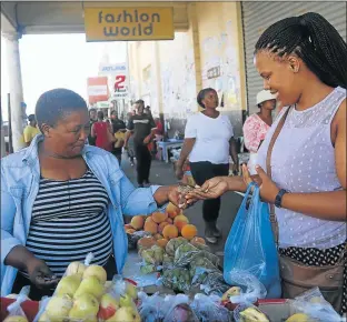  ?? Picture: SIBONGILE NGALWA ?? TIGHT MARGINS: Street vendor Zanele Mluma sells fruit to customer, Mawande Nomnganga in Caxton Street, East London