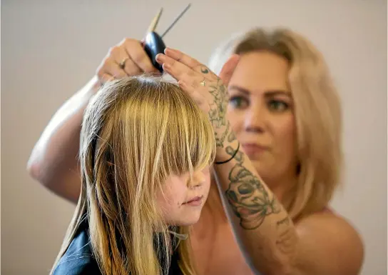  ?? PHOTO: ANDY JACKSON/STUFF ?? Karah Drake, 7, got her hair cut by Rachel Knock from Tangles Hair Design at a fundraiser for the Warren family, who have lost two children this year.