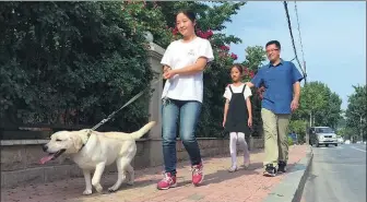  ?? CHENG SI / CHINA DAILY ?? Zhao Qiyi (front) is fostering Bubble, who may be trained as a guide dog, in Dalian.