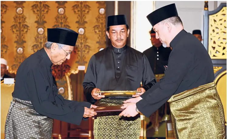  ?? — Bernama ?? It’s official: Yang di-Pertuan Agong Sultan Muhammad V presenting the oath of office to Dr Mahathir at Istana Negara last night.