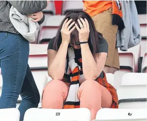  ??  ?? A supporter holds her head in her hands as fellow fans make their way towards the exits.