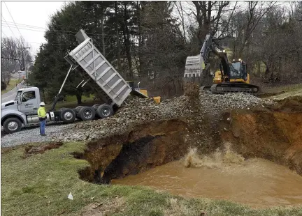  ?? BEN HASTY — MEDIANEWS GROUP ?? A truck delivers another load of rocks while an excavator drops rocks into a hole that opened at a 19th century abandoned iron ore mine along Old Route 100 in Washington Township on Monday.