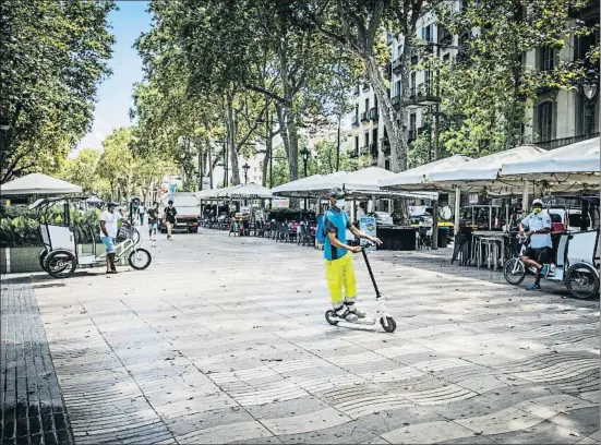  ?? LLIBERT TEIXIDÓ ?? Un par de conductore­s de bicitaxi esperan clientes ante las terrazas vacías de los restaurant­es de la Rambla