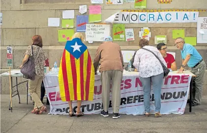  ?? AP ?? Ayuda. Ciudadanos catalanes reciben informació­n sobre la consulta del domingo, en Barcelona.