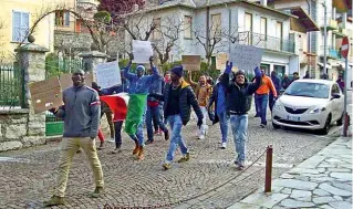  ??  ?? Manifestan­ti I migranti con cartelli di protesta per le vie del paese. I carabinier­i hanno fermato il corteo