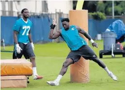  ?? WILFREDO LEE/AP ?? Defensive ends Charles Harris and Arthur Miley (72) run through drills during OTA work this week in Davie.