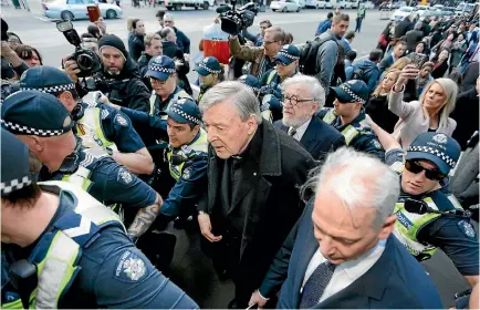  ?? PHOTO: GETTY IMAGES ?? Cardinal George Pell walks with a heavy police guard to the Melbourne Magistrate­s’ Court yesterday. Pell has been charged with sexually abusing multiple people years ago.