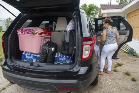  ?? Ap pHotos ?? GETTING READY: Jessica Mejia loads her car with some of her belongings as she and her family prepare to evacuate to Florida from Morgan City, La., on Saturday ahead of the arrival of Hurricane Ida. Below, members of the National Guard enter the New Orleans Ernest N. Morial Convention Center on Saturday.