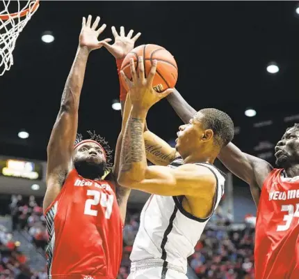  ?? MEG MCLAUGHLIN U-T ?? Aztecs forward Keshad Johnson has a hard time trying to get a shot against New Mexico forwards Morris Udeze (24) and Birima Seck.