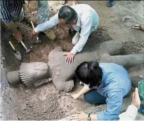  ?? — AFP ?? Significan­t find: Archaeolog­ists unearthing the large, centuries-old statue at the Angkor temple complex.