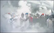  ?? AFP ?? Farmers gather along a road amid smoke during fumigation by the municipal corporatio­n at the Ghaizpur border on Tuesday to stop farmers from marching to Delhi.