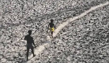  ?? AP PHOTO/MANISH SWARUP ?? A man and a boy walk across the almost dried up bed of river Yamuna following hot weather in New Delhi, India, on May 2.