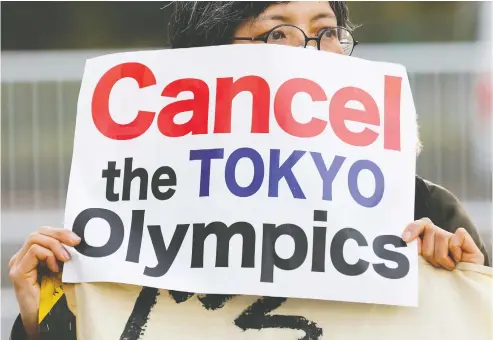  ?? KIM KYUNG-HOON / REUTERS ?? A woman holds a banner Friday in Tokyo during a rally in front of a building housing the organizing committee of the Olympic Games to demand
the Games' cancellati­on and to criticize sexist comments made by former organizing committee chief Yoshiro Mori.
