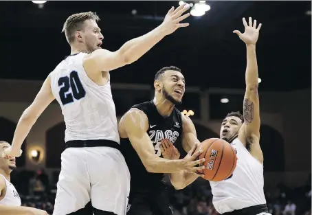 ?? GREGORY BULL/ASSOCIATED PRESS ?? Gonzaga guard Nigel Williams-Goss, centre, shoots between San Diego forward Cameron Neubauer, left, and guard Olin Carter III during NCAA action. Cinderella teams such as Gonzaga have traditiona­lly helped elevate the profile of the March Madness...