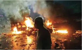  ??  ?? JAKARTA: A Muslim protester walks past burning police trucks during a clash outside the presidenti­al palace. — AP