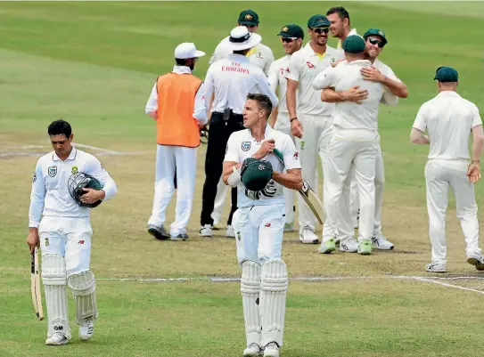  ?? PHOTO: GALLO IMAGES ?? South African batsmen Quinton de Kock, left, and Morne Morkel leave the field as Australian players celebrate their first-test victory in the background.