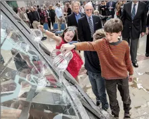  ?? Arkansas Democrat-Gazette/STEPHEN B. THORNTON ?? Caroline Michaels (left), 9, Charlie Nichols, 8, and James Nichols, 11, pour river water on the sculpture Straight Lines on a Round World during the dedication of the artwork Monday morning in front of the Statehouse Convention Center in downtown...