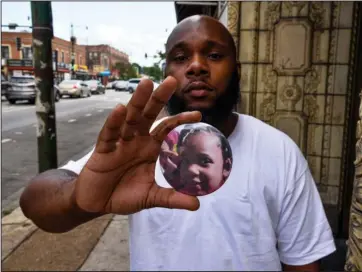  ?? The Associated Press ?? BUTTON: Nathan Wallace stands outside of his home holding a button showing his daughter, Natalia Wallace, on Monday, in Chicago. Natalia, 7, was killed on the west side of Chicago on July 4.