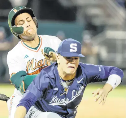  ?? AL DIAZ adiaz@miamiheral­d.com ?? UM outfielder Edgardo Villegas collides with Penn State first baseman Anthony Steele in the first inning in Coral Gables on Friday.