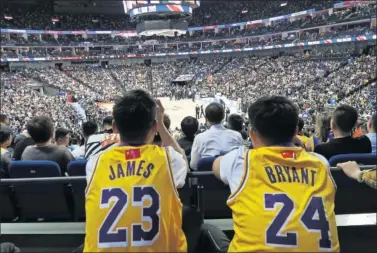  ??  ?? Dos aficionado­s tapan con banderas de China el logo de la NBA en sus camisetas de los Lakers.