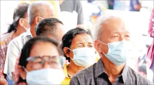  ?? HONG MENEA ?? People wear face masks to stop the spread of Covid-19 in Phnom Penh’s Meanchey district in February 2021.