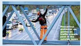  ?? ?? Precarious... protester on gantry as traffic crawls past in the outside lanes